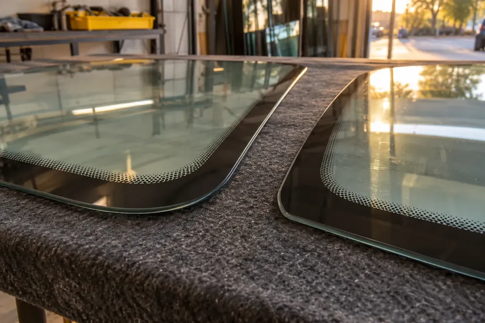Two windshield corners side by side with small printed markings and black border dots