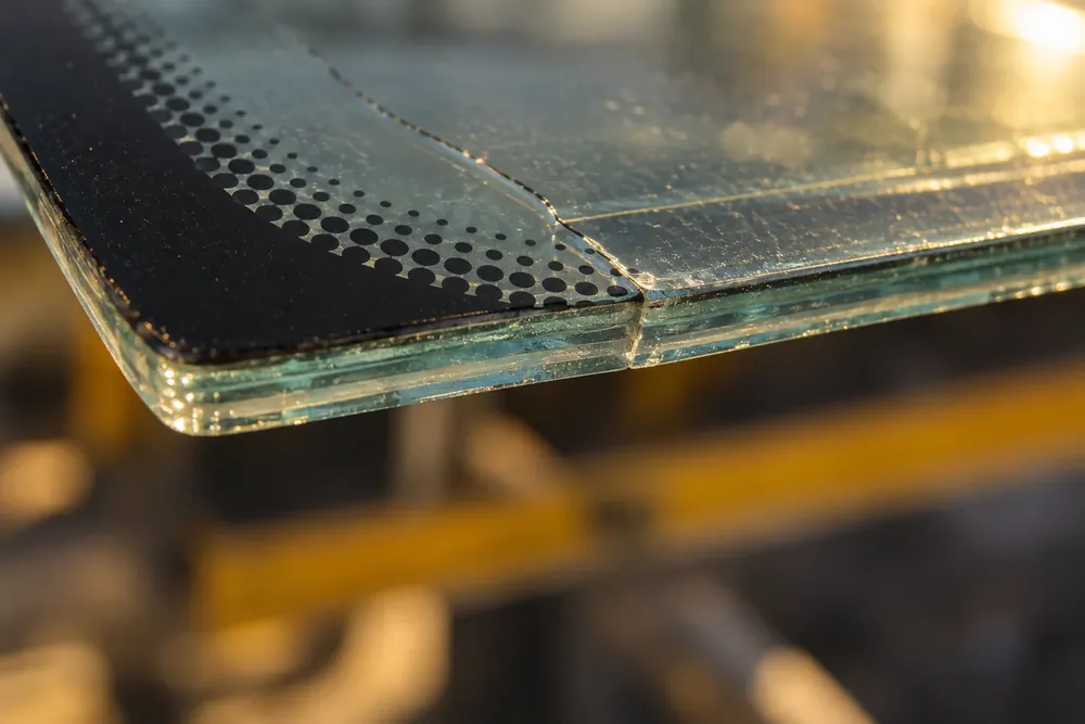 Cracked windshield edge showing a clear plastic layer between two glass sheets