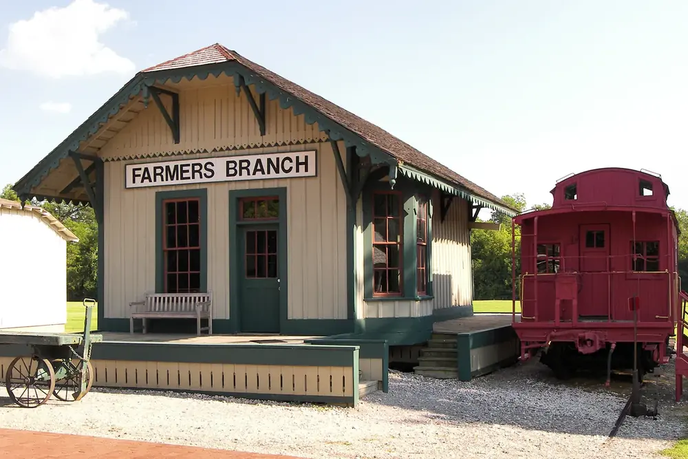 Restored Farmers Branch railroad depot with a red caboose beside it in Farmers Branch, Texas