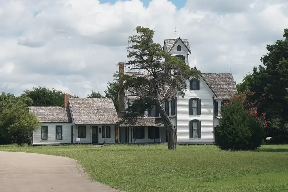 Historic Stephen Decatur Lawrence Farmstead house with a lawn and a tall tree in Mesquite, Texas