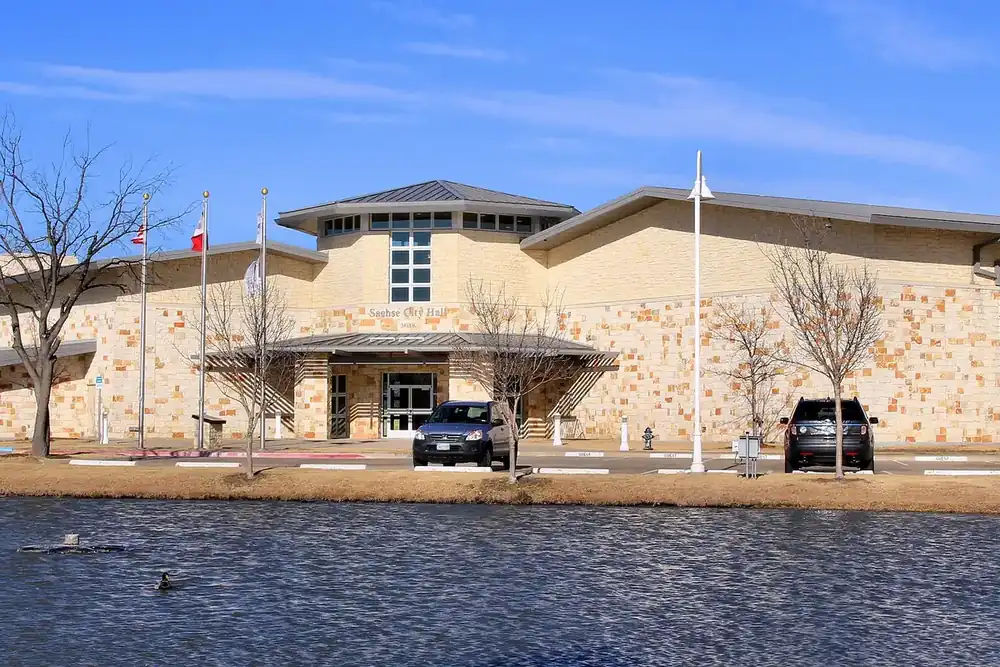 Sachse City Hall with a stone front beside a small pond in Sachse, Texas