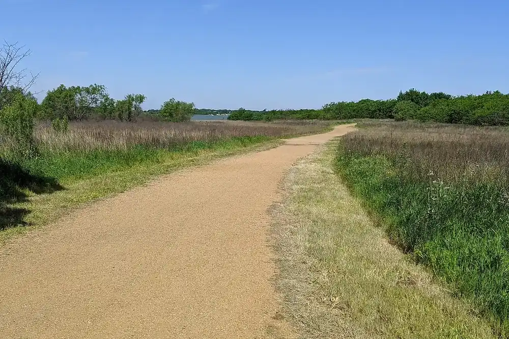 Dirt trail through prairie grass toward Lewisville Lake at Ridgepointe Park in The Colony, Texas